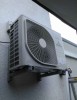 A Mitsubishi air conditioning outdoor unit mounted on an exterior wall, with a large fan visible in the center of the unit.